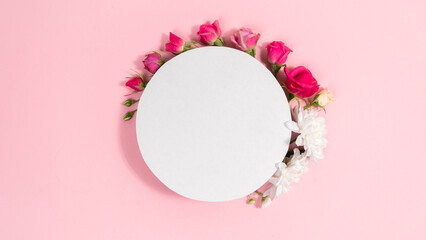 White circle background is decorated natural flowers buds. Pink background. Template for text or design.