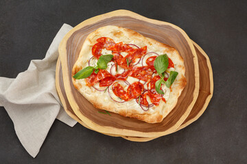 Crispy Gourmet pepperoni pizza with salami and basil leaves on wooden kitchen boards. Top view