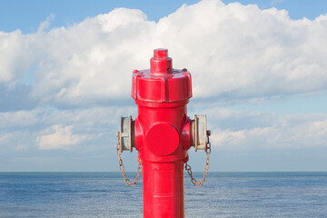 An improbable hydrant at the seaside - Plenty of water concept image with red hydrant against ocean