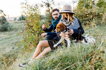 couple is walking in the park playing with a beagle dog having fun