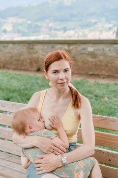 Young caucasian woman breastfeeding her baby girl in a park