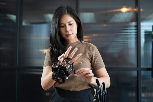 Asian female engineer working with AI robot arm system. Female engineer control robot arm with her hands. Asian female constructing robot arm system project. Programmable logic controller concept