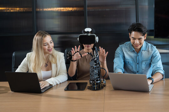 Male and female engineer working with vr glasses control AI robot arm system in workshop. Male engineer using laptop computer for training Programmable logic controller robotics arm system project