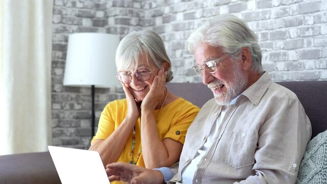 Excited senior mature couple surprised by good unbelievable news, unexpected win, huge shopping sale offer on website, astonished older middle aged family looking at computer screen feeling amazed