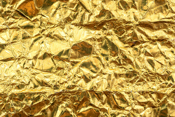 Luxurious golden foil texture. Crumpled yellow foil with scuffs and waves
