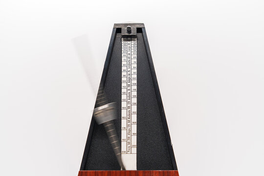Old fashioned metronome with blurred arm indicating motion isolated on a white background