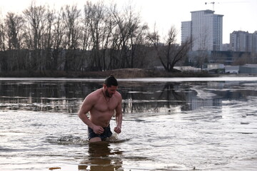 Winter swimming in ice water. January weather, Epiphany frosts and a man bathing.
Athletic believing man bathes in a pond
