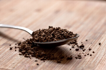 Instant coffee in an iron spoon on a wooden table