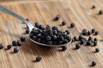 Black peppercorns on a spoon. Dried round peppers on a spoon