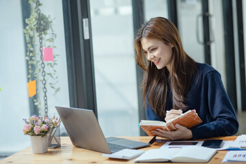 Happy smiling young asian business woman paper notebook and laptop in the office, Company worker...