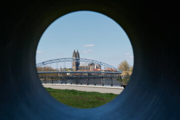 View of Magdeburg Cathedral and Stern Bridge through the hole of a sculpture on the bank of the...