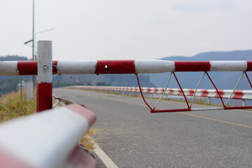 Guardrail traffic barrier painted red and white block the road line on crest reservoir dam. - Powered by Adobe