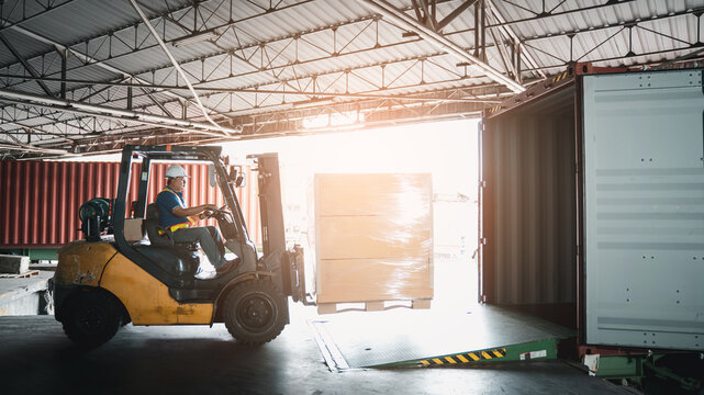 Warehouse worker workers with forklift in a warehouse. Use forklift operator moves packages. Concept industrial and commercial.