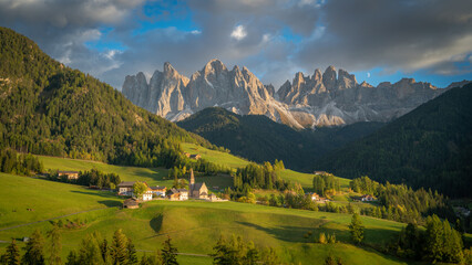 Panoramic of Santa Maddalena, Dolomites, Italy. Green valley landscape with snowy mountains in the background.