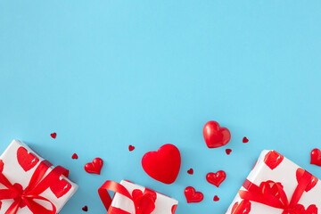 Valentine's Day gift concept. Flat lay composition made of gift boxes with silk ribbon and red hearts on pastel blue background with copy space. Lovers holiday card idea.
