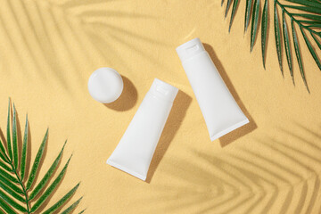 Sunscreen cosmetic concept. Flat lay photo of cosmetic bottles without label, green tropical leaves...