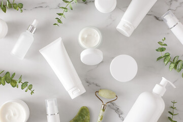 Skin care products concept. Flat lay photo of white cosmetic bottles, cream jars, dropper bottles,...