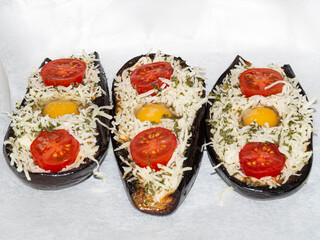 Tres berenjenas rellenas con mozarela, tomates y huevos, muy apetitoso, para meter al horno y gratinar.