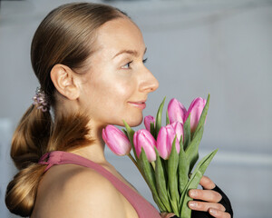 Profile of a girl in a sports bodysuit with a bouquet of pink tulips in her hands