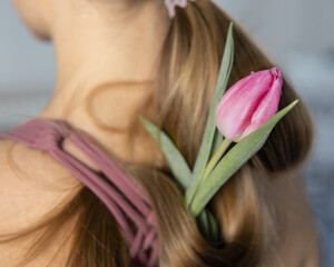 Naklejka premium Delicate pink tulip in long blonde girl's hair