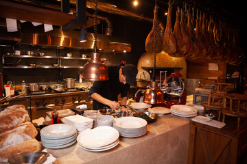Professional cook. chef in black apron and cap working in restaurant kitchen
