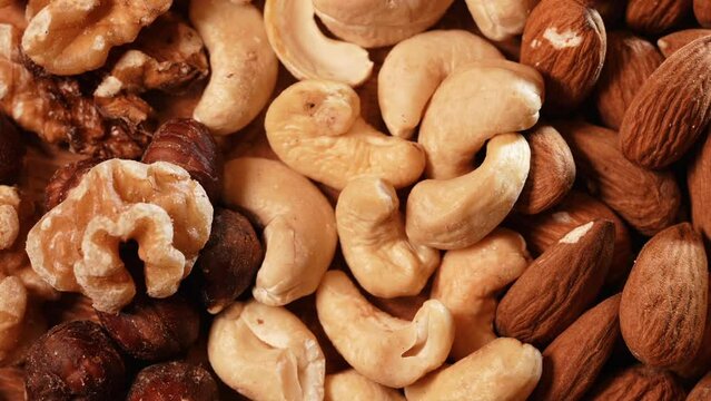Nuts, cashews, almonds and Brazilian nuts from above. Mix with different types of nuts on a wooden plate. macro healthy food with proteins, 4k video, pan camera movement.