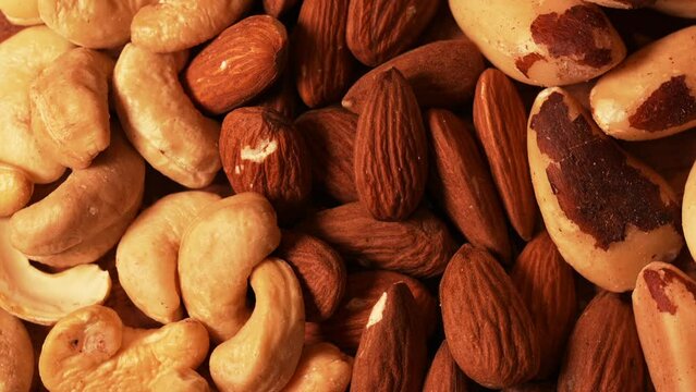 Mix with different types of nuts on a wooden plate. 4k video with Nuts, cashews, almonds and Brazilian nuts. Healthy food with proteins.
