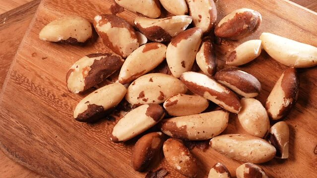 Brazilian nuts on a wooden table. Detail 4k video with healthy nuts rich in Selenium and other vitamins and proteins, pan camera movement.