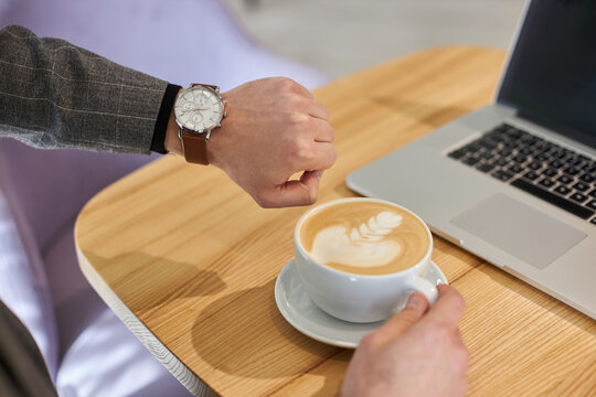 Personal perspecctive view of a businessman cheks the time on his wristwatch while a coffee break
