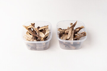 Dried mushrooms in plastic containers on white background. Storage of dried mushrooms