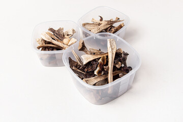 Dried mushrooms in plastic containers on white background. Storage of dried mushrooms. Food containers of different sizes