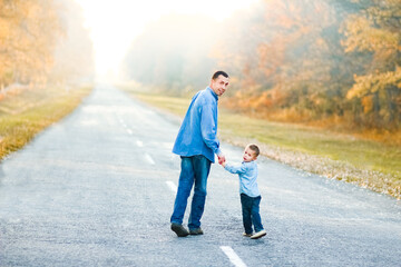 A Happy parent with child are walking along the road in the park on nature travel