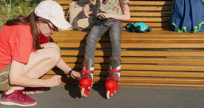 Woman tightens bindings on her daughter's roller skates to prevent injuries while roller skating