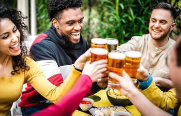 Multicultural friends drinking beer at brewery pub garden - Genuine friendship life style concept with guys and girls enjoying happy hour time together at open air bar dehor - Bright vivid filter