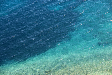 Azure water texture, transparent sea surface with a rocky bottom. Aerial view, natural turquoise background
