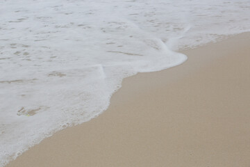 Foamy waves over sand on the tropical beach.