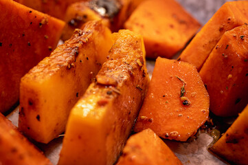 Roasted pumpkin on a light parchment background. Close up view, selective focus. Healthy food
