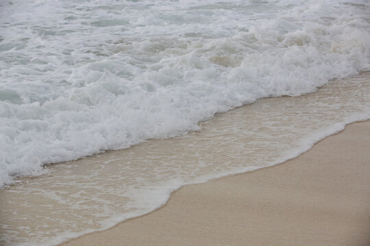 Foamy waves over sand on the tropical beach.