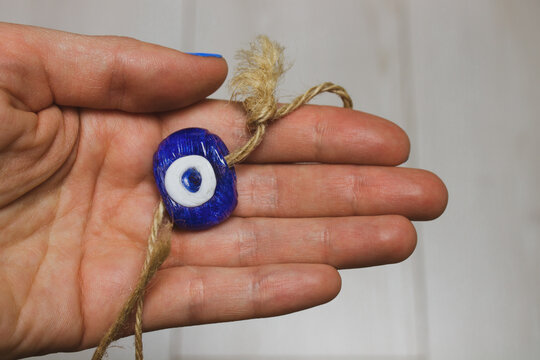Glass pendant against the evil blue eye. Turkish amulet in a woman's hand. Bead in the form of an eye protecting from evil forces. Religious symbol protecting people. Eastern souvenir. Arabic charm.