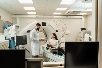 Naklejka premium CT Doctor consulting patient and showing brains x-ray to patient in computed tomography room. CT scan radiologist showing x-ray of brains to girl patient in computed scanning room.