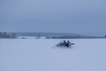 Fototapeta premium Hunters on snowmobiles ride in the winter forest