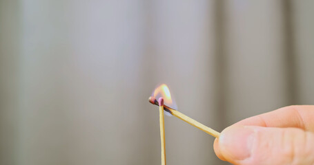 Male hand sets fire to one match from another. Close-up.