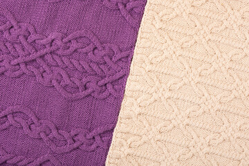 Knitted lilac and beige background. Large knitted fabric with a pattern. Close-up of a knitted blanket.