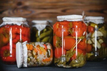 Jars of pickled vegetables on rustic wooden background