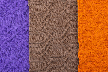 Knitted brown, lilac and orange background. Large knitted fabric with a pattern. Close-up of a knitted blanket. Banner