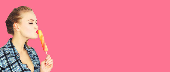 Portrait of beautiful young woman enjoying sweet ice cream or lollipop on pink background, blank...