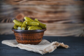 Pickled gherkins or cucumbers in bowl on wooden rustic table from above.