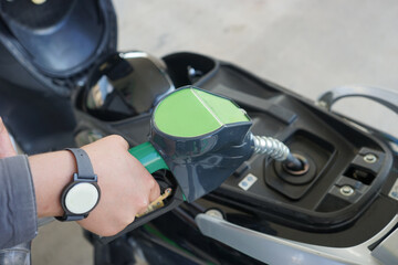 Pumping gas at gas pump. girl hand pumping gasoline fuel in motorcycle at gas station. Close-up...