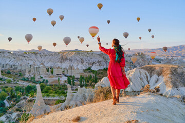 Bogo girl traveler vacations beautiful destination in Goreme, Turkey. Fabulous Kapadokya with flying air balloons at sunrise, Anatolia