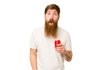 Young adult long beard man drinking a cola isolated shrugs shoulders and open eyes confused.